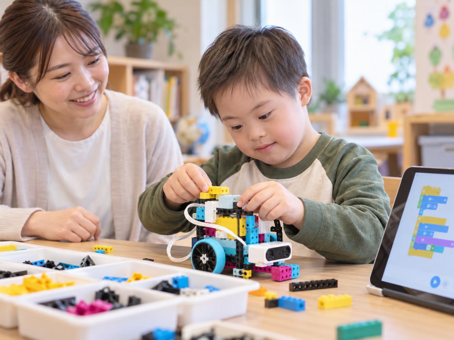 LEGO SPIKEのブロックを組み立てる子どもとプログラミング画面