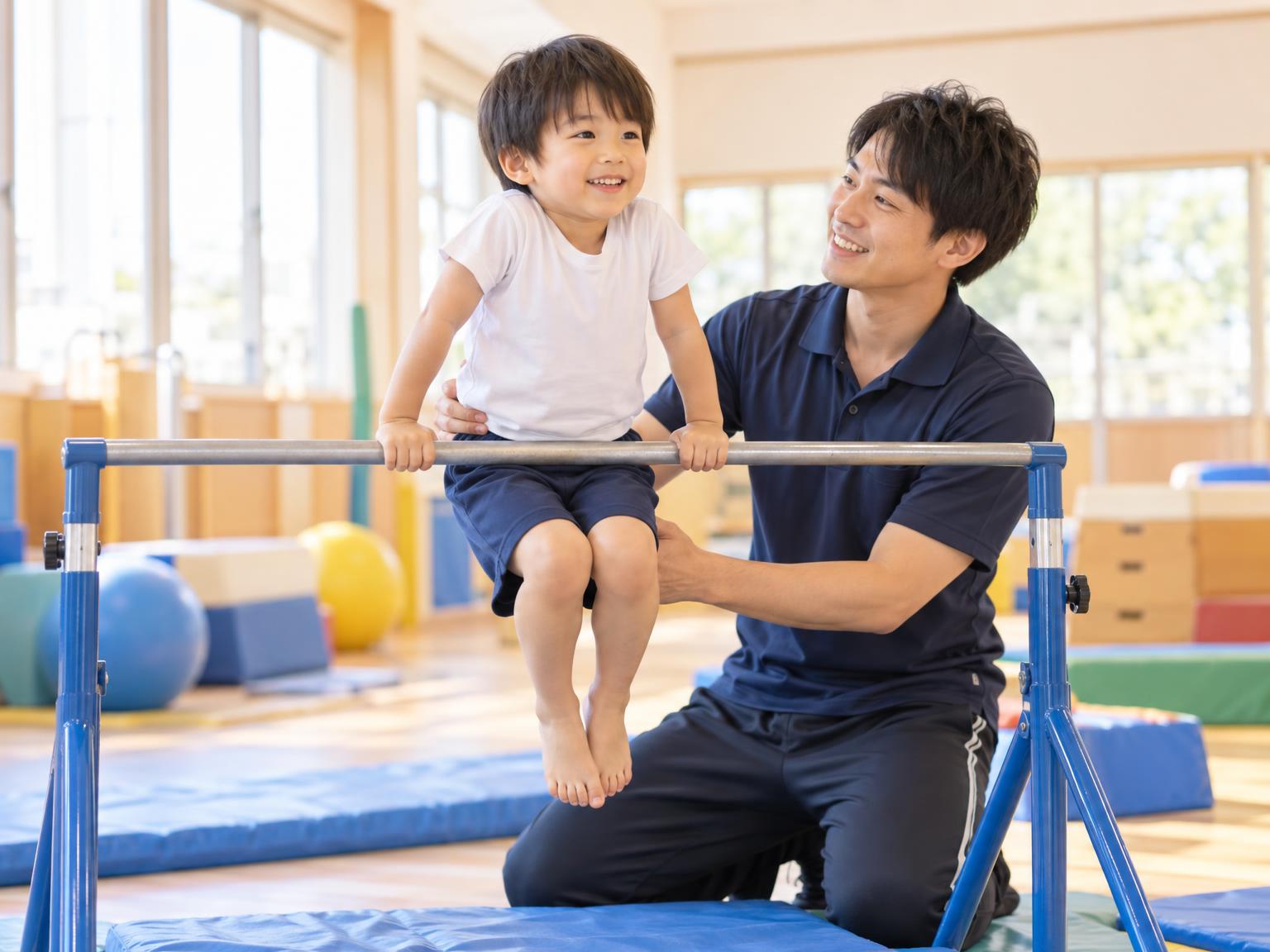 マンツーマンで鉄棒の練習をする子どもと指導者