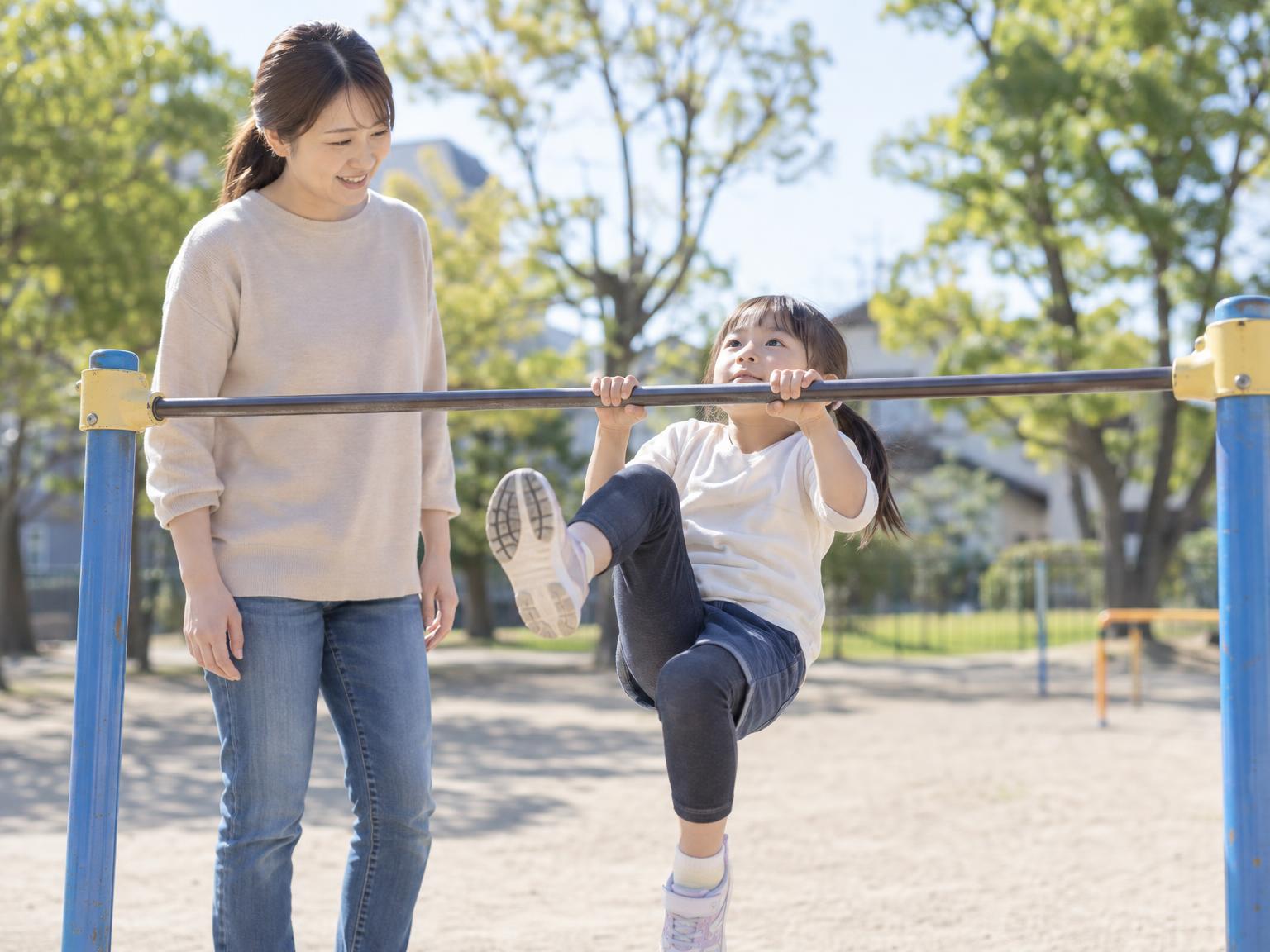 保護者が横から子どもの逆上がりの動きを観察している場面