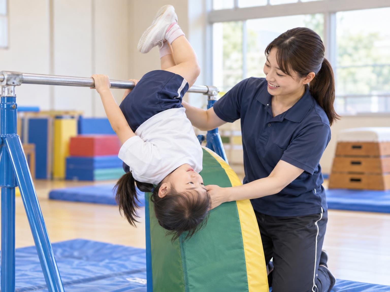 補助具を使って逆上がりを練習する子どもと指導者