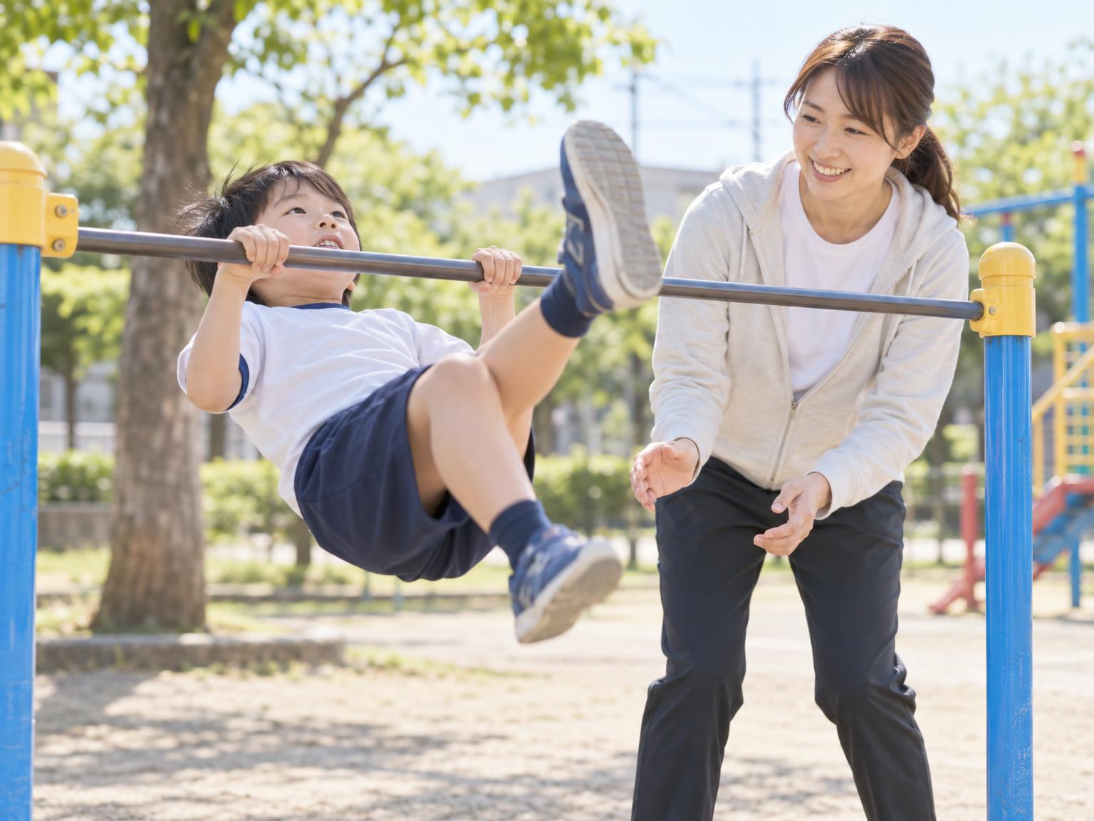 逆上がりを練習する小学生と見守る大人