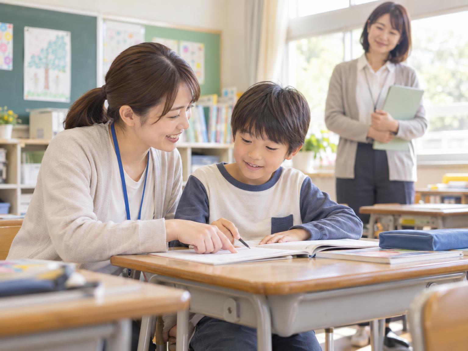 支援者が学校で子どもに寄り添いながら担任と連携している様子のイメージ