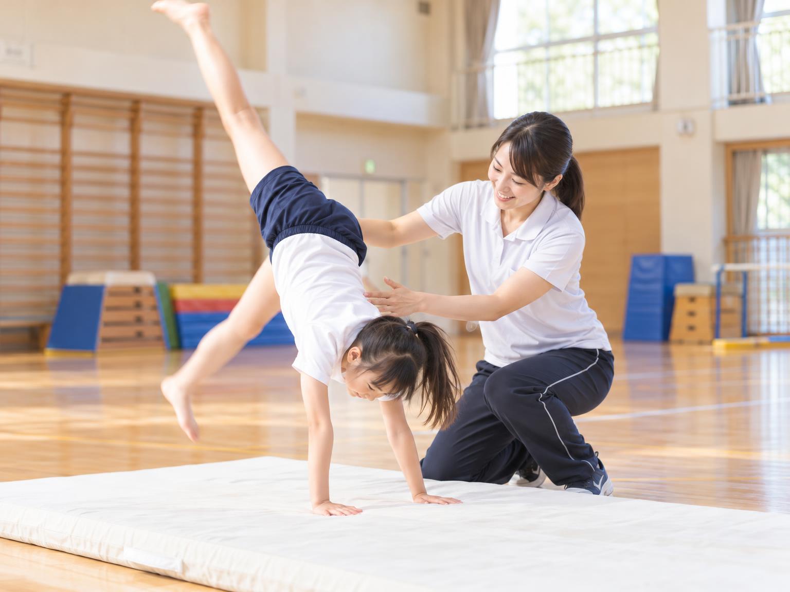 補助具を使ってアクロバットの練習をする小学生と講師