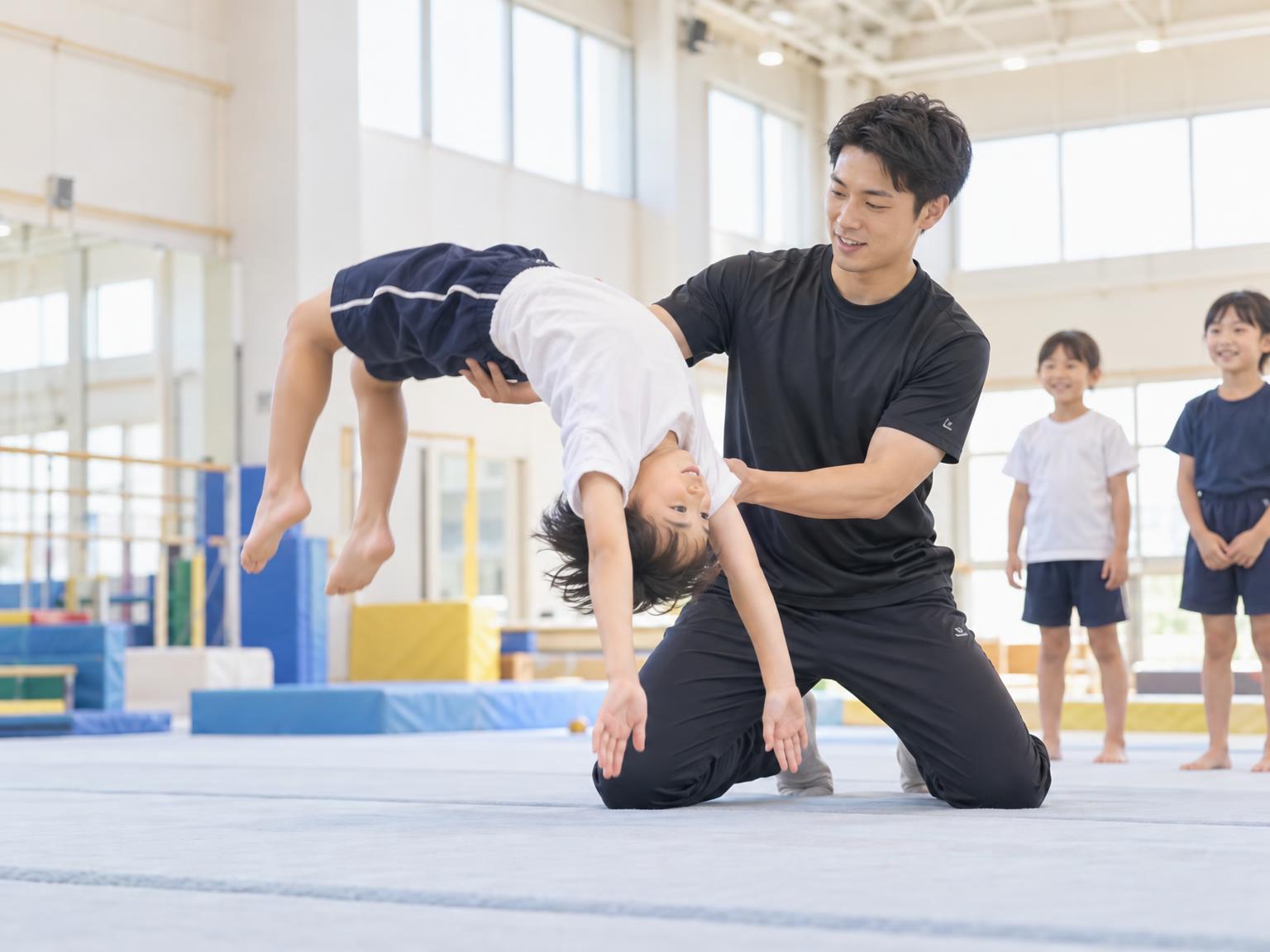 インストラクターが補助しながら子どもがバク転の練習をしている様子