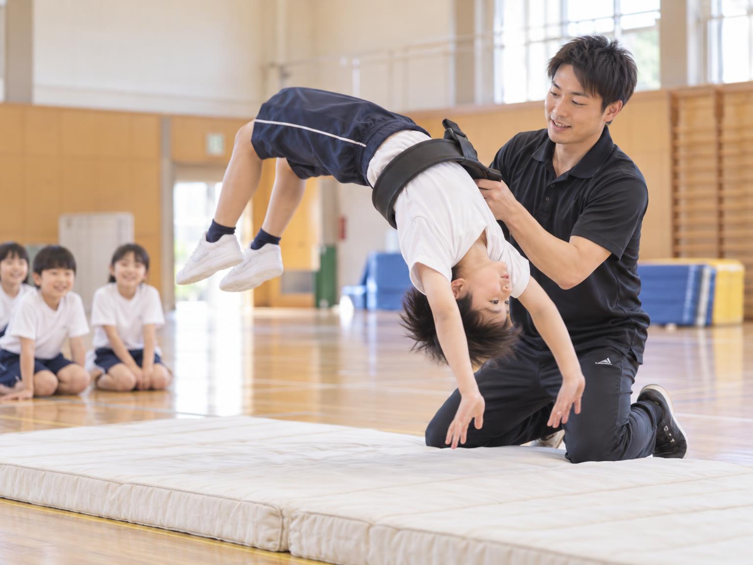 バク転の練習をする子どもと補助する講師