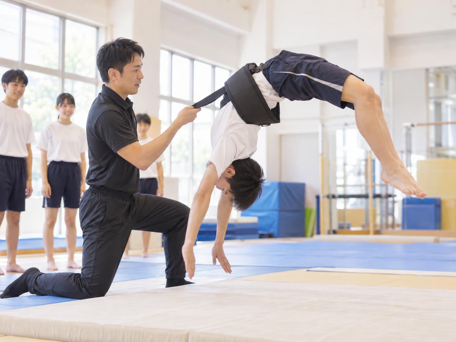 中学生がバク転の練習をしている体操教室の様子