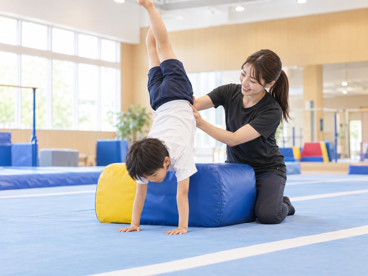 講師が補助具を使って子どものアクロバット練習をサポートしている様子
