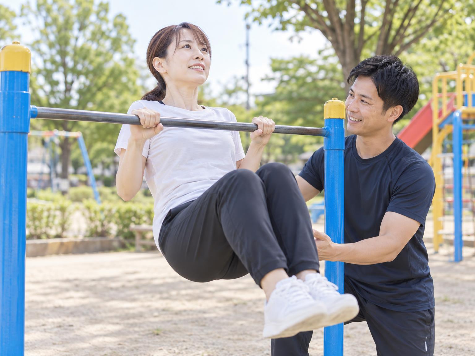 大人が鉄棒で逆上がりの練習をしている様子