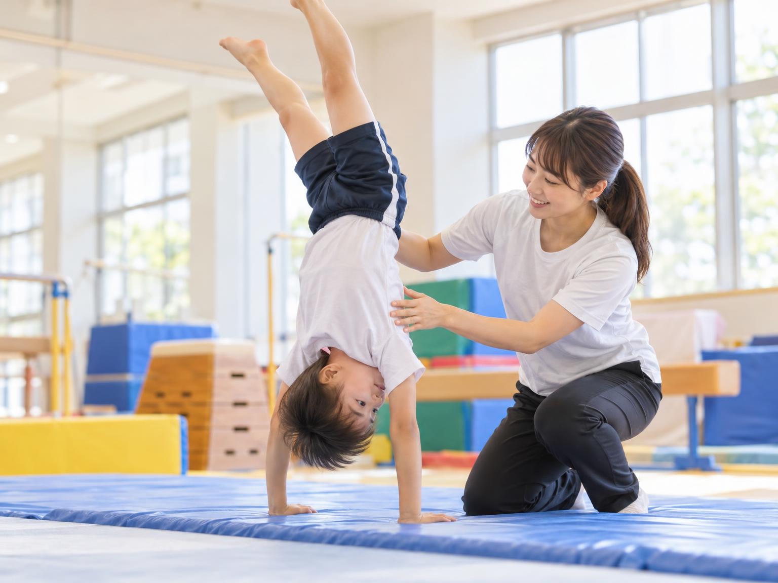 コーチが補助しながら子どもがアクロバットを練習している室内ジムの様子