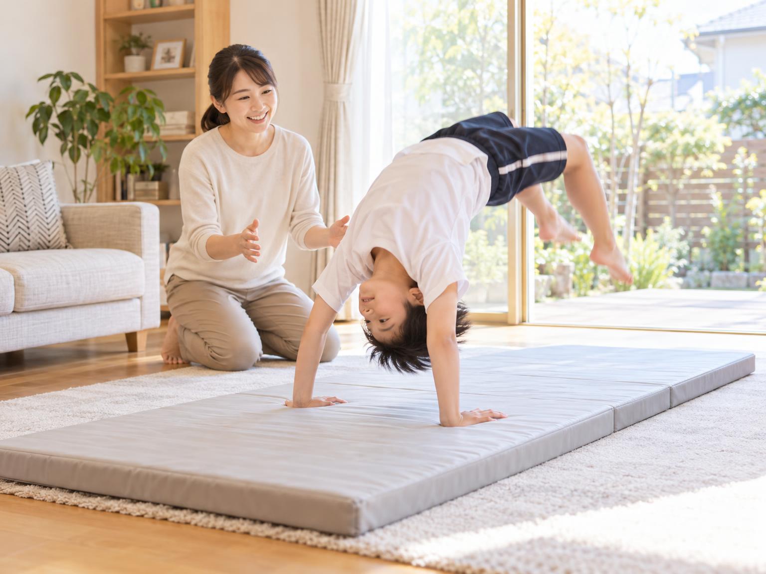 自宅でタンブリングマットを使って練習する子どもと見守る保護者