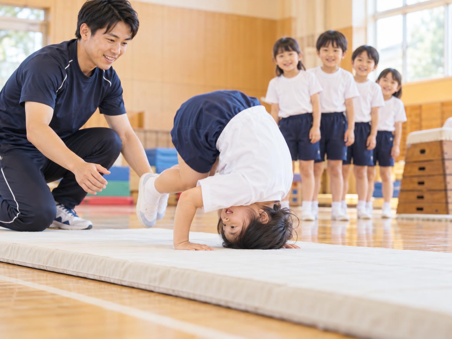 体操教室で前転を練習する小学生