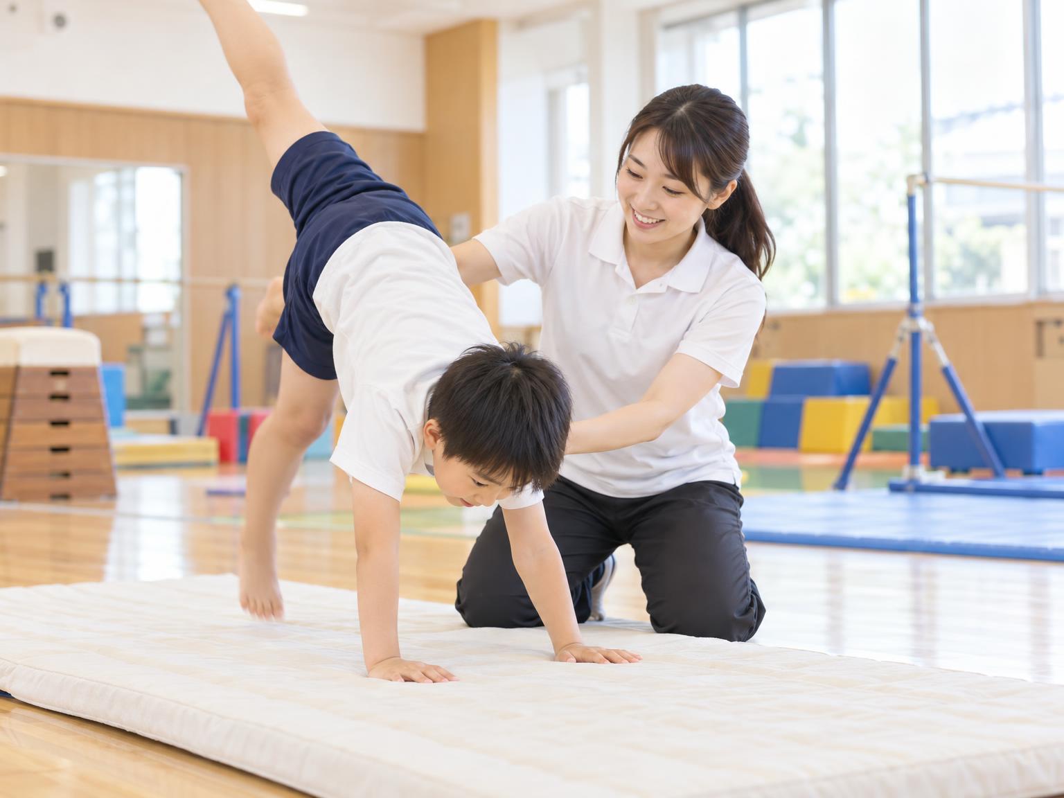 インストラクターと一対一で体操の練習をする子ども