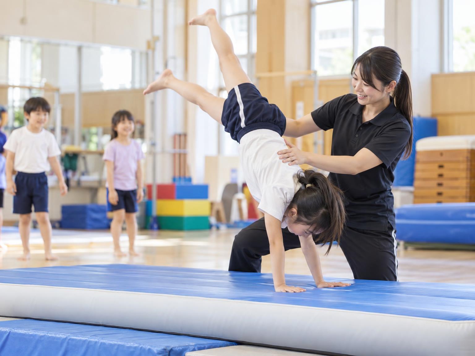 講師の補助を受けながらアクロバット練習をする小学生