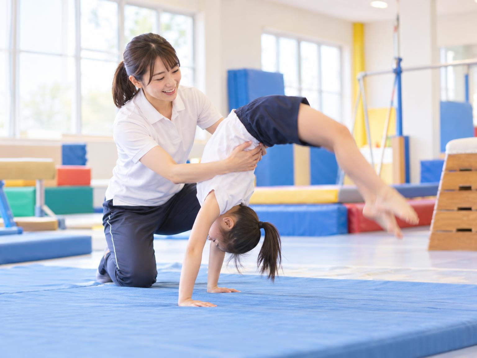 コーチが補助しながら子どもがバク転の練習をしている様子