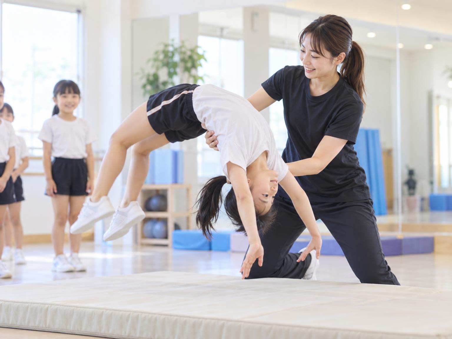 子どもがアクロバット教室でバク転の補助練習をしている様子