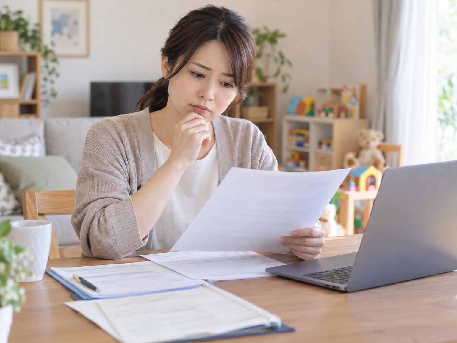 書類とパソコンを前に考え込む保護者のイメージ